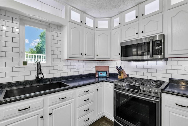 956 E Orleans St, Paxton, IL 60957 - kitchen featuring appliances with stainless steel finishes, a sink, dark countertops, white cabinets, and a textured ceiling