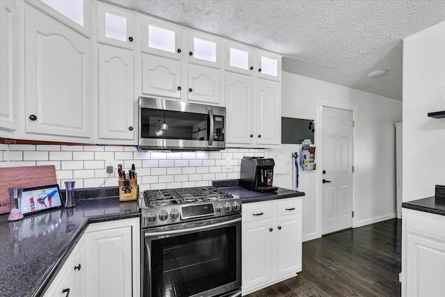 956 E Orleans St, Paxton, IL 60957 - kitchen featuring stainless steel appliances, dark countertops, dark wood-style floors, glass insert cabinets, and a textured ceiling