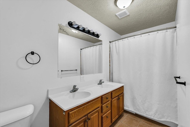 956 E Orleans St, Paxton, IL 60957 - bathroom featuring toilet, a textured ceiling, double vanity, and tile patterned floors