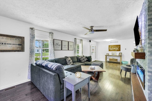 956 E Orleans St, Paxton, IL 60957 - living room featuring a ceiling fan, dark wood finished floors, baseboards, a textured ceiling, and a glass covered fireplace