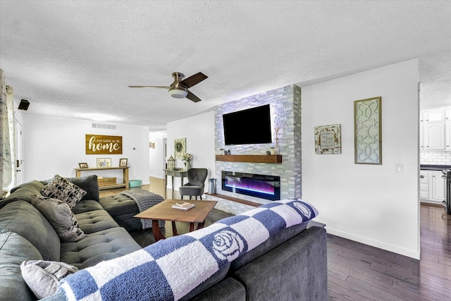 956 E Orleans St, Paxton, IL 60957 - living area featuring a textured ceiling, a ceiling fan, dark wood-style flooring, a fireplace, and baseboards