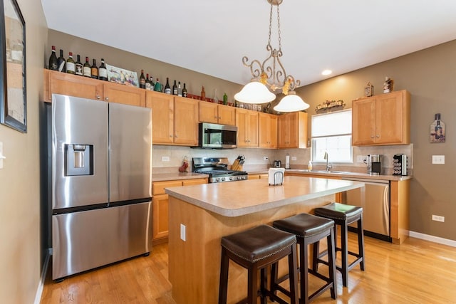 13555 Golden Eagle Cir, Plainfield, IL 60544 - kitchen with appliances with stainless steel finishes, a sink, light countertops, light wood finished floors, and decorative backsplash
