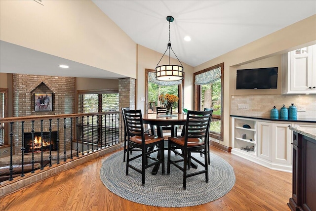 10348 Woburn Ct, Orland Park, IL 60462 - dining area with light wood-type flooring, vaulted ceiling, a brick fireplace, and recessed lighting