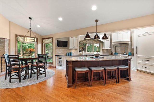 10348 Woburn Ct, Orland Park, IL 60462 - kitchen featuring a center island, white cabinetry, backsplash, a kitchen breakfast bar, and light wood-style floors