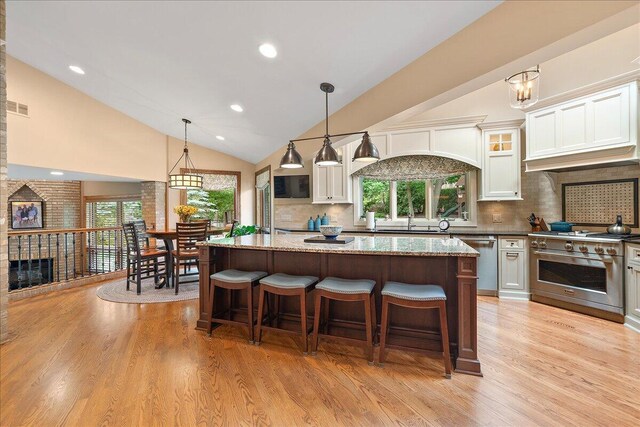 10348 Woburn Ct, Orland Park, IL 60462 - kitchen with appliances with stainless steel finishes, light wood finished floors, a center island, decorative backsplash, and high vaulted ceiling