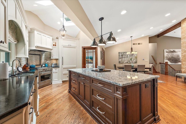 10348 Woburn Ct, Orland Park, IL 60462 - kitchen with vaulted ceiling, stainless steel range, light wood-type flooring, a kitchen island, and white cabinetry