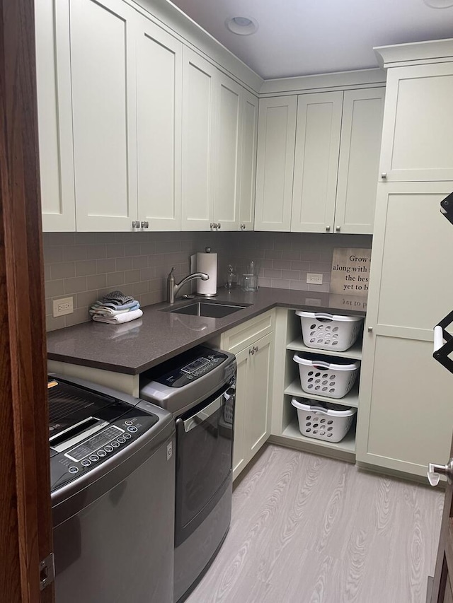 10348 Woburn Ct, Orland Park, IL 60462 - kitchen featuring a sink, washer and dryer, dark countertops, light wood finished floors, and backsplash