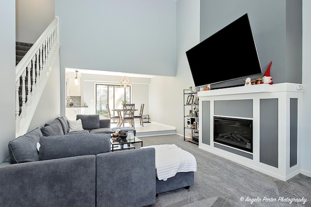 638 Dordan Ct, Gurnee, IL 60031 - carpeted living room featuring a high ceiling, stairway, baseboards, a chandelier, and a glass covered fireplace