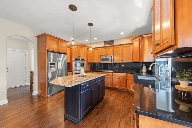 12923 Grande Pines Blvd, Plainfield, IL 60585 - kitchen with stainless steel appliances, a sink, arched walkways, a center island, and brown cabinets