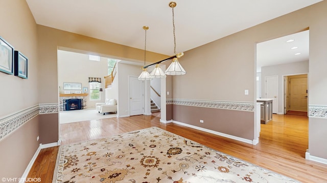 296 Huron St, Vernon Hills, IL 60061 - unfurnished dining area with light wood finished floors, stairway, a lit fireplace, and baseboards