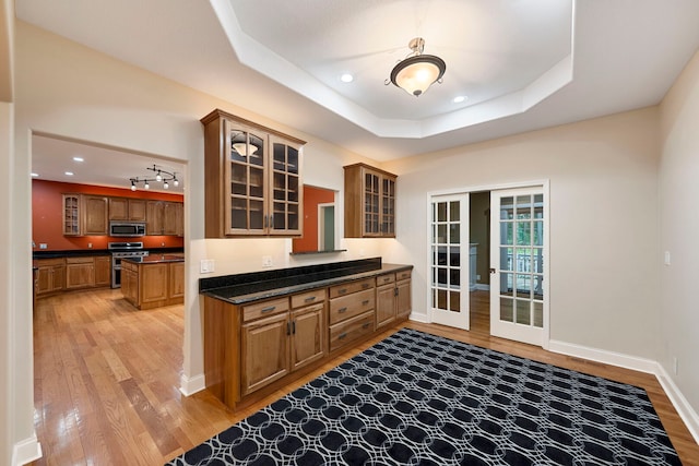 1912 Indian Trl, Kankakee, IL 60901 - kitchen featuring appliances with stainless steel finishes, light wood-style floors, dark countertops, french doors, and glass insert cabinets