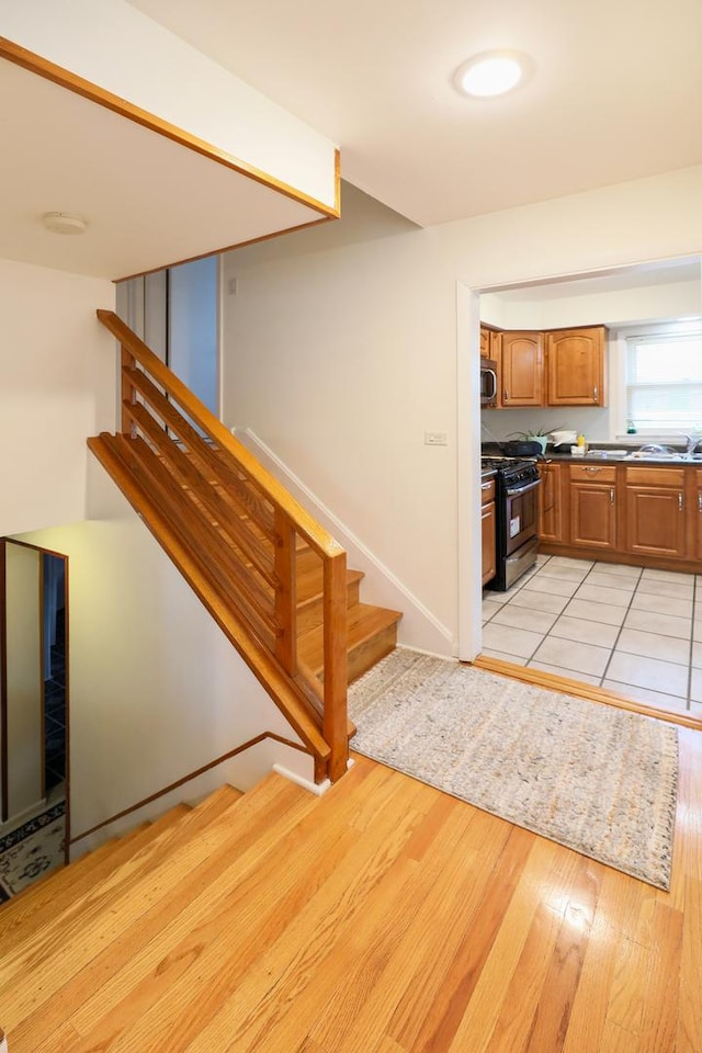 1065 Irwin Ave, Des Plaines, IL 60018 - kitchen with black range with gas cooktop, light wood-type flooring, brown cabinetry, and stainless steel microwave