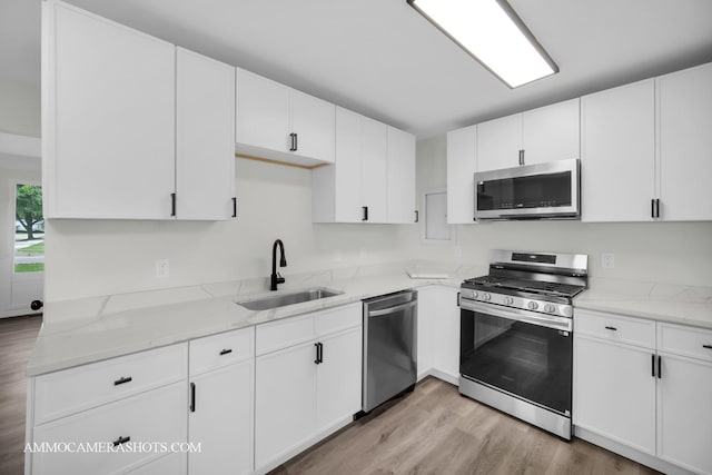 1306 Schriber Ave, Joliet, IL 60435 - kitchen featuring appliances with stainless steel finishes, a sink, light wood-style floors, and light stone counters