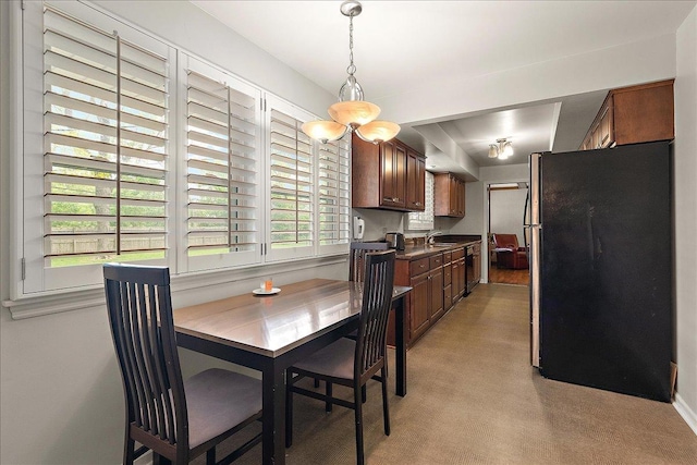 20424 Ithaca Rd, Olympia Fields, IL 60461 - kitchen featuring freestanding refrigerator, dark countertops, a sink, hanging light fixtures, and brown cabinetry