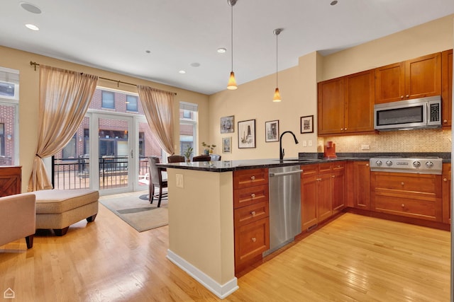 2862 N Paulina St, Chicago, IL 60657 - kitchen with appliances with stainless steel finishes, a sink, light wood-style flooring, a peninsula, and recessed lighting