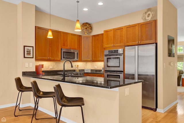 2862 N Paulina St, Chicago, IL 60657 - kitchen featuring stainless steel appliances, a sink, a peninsula, light wood-style floors, and recessed lighting