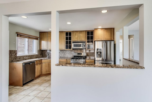7665 W Victoria St, Chicago, IL 60631 - kitchen featuring appliances with stainless steel finishes, decorative backsplash, dark stone countertops, glass insert cabinets, and brown cabinetry