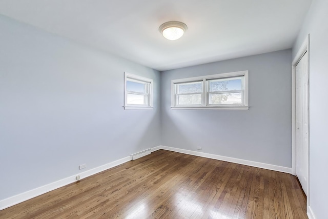 7665 W Victoria St, Chicago, IL 60631 - unfurnished bedroom with wood finished floors, baseboards, a baseboard radiator, and a closet