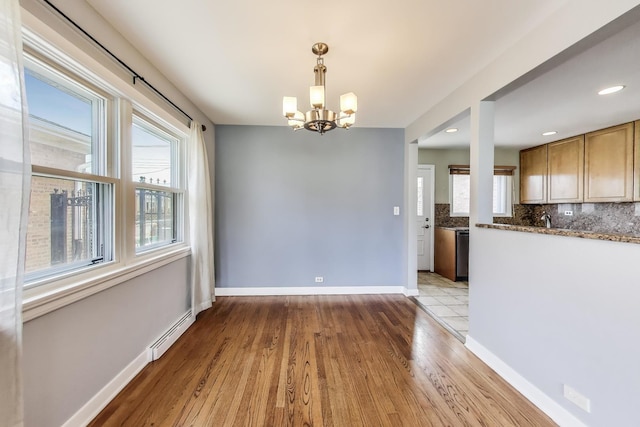 7665 W Victoria St, Chicago, IL 60631 - unfurnished dining area featuring baseboard heating, a chandelier, wood finished floors, baseboards, and a sink