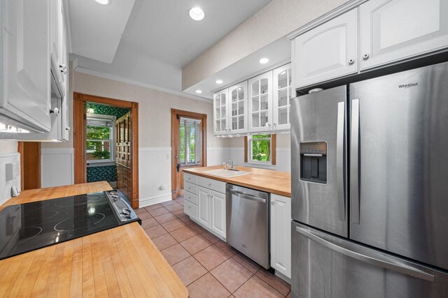 508 Grant St, Earlville, IL 60518 - kitchen featuring butcher block countertops, appliances with stainless steel finishes, wainscoting, glass insert cabinets, and white cabinets