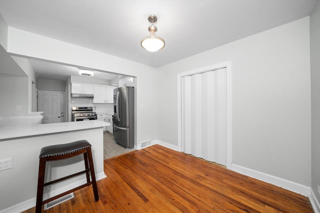 3900 Home Ave, Stickney, IL 60402 - kitchen featuring stainless steel appliances, light countertops, white cabinets, a peninsula, and a kitchen bar