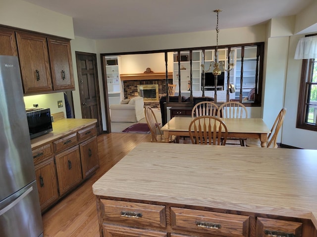 1263 Bainbridge Dr, Naperville, IL 60563 - kitchen with freestanding refrigerator, light wood-type flooring, a fireplace, and a chandelier