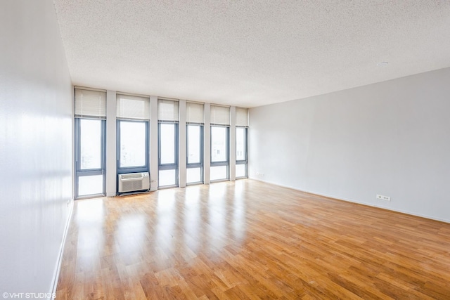 6700 S S Shore Dr Unit 5E, Chicago, IL 60649 - unfurnished room with a textured ceiling, light wood-type flooring, and a wall mounted air conditioner