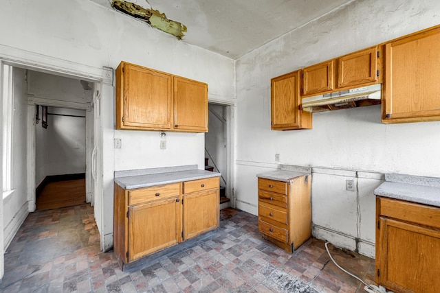 4728 S Evans Ave, Chicago, IL 60615 - kitchen with under cabinet range hood, light countertops, brick patterned flooring, and brown cabinetry