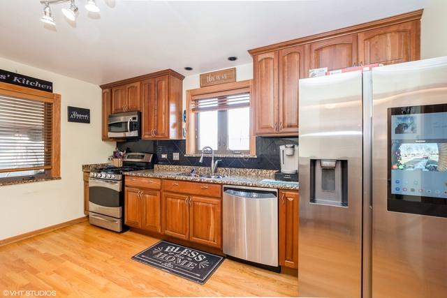 2535 W 116th Pl, Chicago, IL 60655 - kitchen with appliances with stainless steel finishes, a sink, dark stone countertops, backsplash, and light wood-style flooring