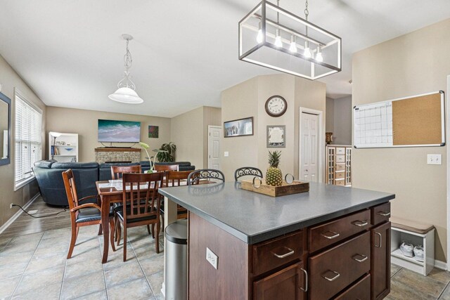 1885 W Greenleaf Ct, Round Lake, IL 60073 - kitchen featuring a fireplace, dark countertops, baseboards, hanging light fixtures, and dark brown cabinetry