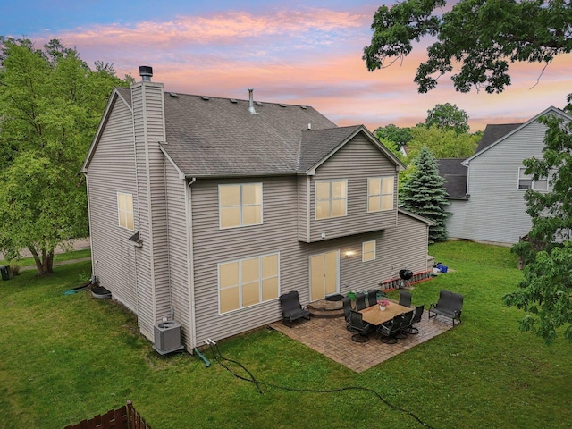 1885 W Greenleaf Ct, Round Lake, IL 60073 - back of property at dusk featuring a patio area, a chimney, a yard, and roof with shingles