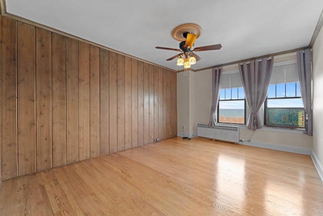 3530 N Lake Shore Dr Unit 12B, Chicago, IL 60657 - spare room featuring radiator heating unit, a ceiling fan, light wood-style flooring, wood walls, and baseboards