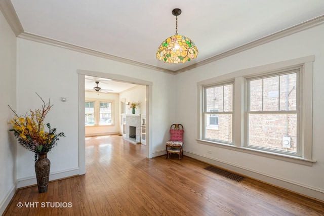 3726 Kenilworth Ave, Berwyn, IL 60402 - empty room featuring ornamental molding, wood-type flooring, baseboards, a brick fireplace, and ceiling fan