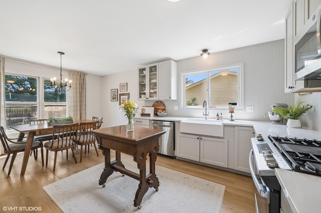204 Barnwood Trl, Mchenry, IL 60050 - kitchen featuring appliances with stainless steel finishes, a chandelier, glass insert cabinets, light countertops, and light wood-style floors