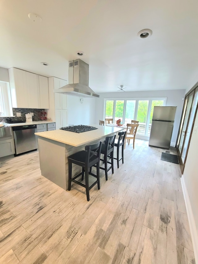 15285 State St, South Holland, IL 60473 - kitchen featuring wall chimney range hood, stainless steel appliances, light wood finished floors, and white cabinetry