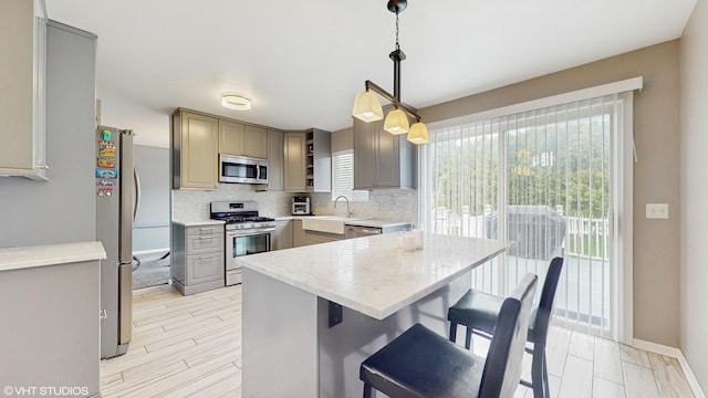 412 Joshua Tree, Harvard, IL 60033 - kitchen with stainless steel appliances, gray cabinets, backsplash, a breakfast bar area, and hanging light fixtures