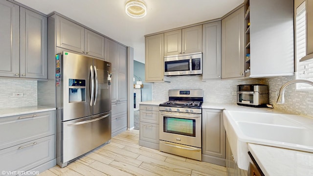 412 Joshua Tree, Harvard, IL 60033 - kitchen with appliances with stainless steel finishes, gray cabinetry, a sink, light countertops, and decorative backsplash