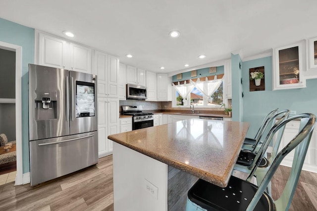 5640 W 82nd Pl, Burbank, IL 60459 - kitchen featuring stainless steel appliances, a sink, white cabinetry, a breakfast bar, and stone countertops