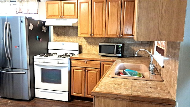 4542 S Lamon Ave, Chicago, IL 60638 - kitchen with stainless steel appliances, under cabinet range hood, a sink, dark wood-style floors, and brown cabinetry