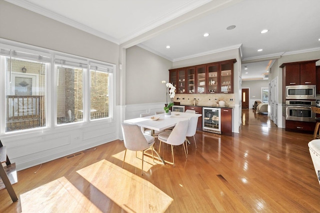 6205 W Grace St, Chicago, IL 60634 - dining space with beverage cooler, crown molding, bar, wood finished floors, and wainscoting