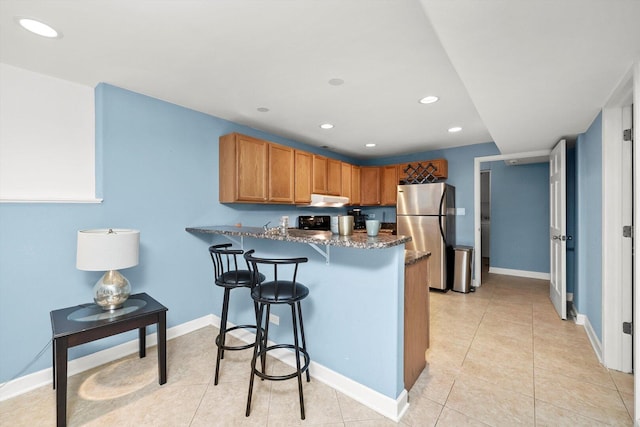 6205 W Grace St, Chicago, IL 60634 - kitchen with freestanding refrigerator, a peninsula, recessed lighting, baseboards, and dark stone countertops