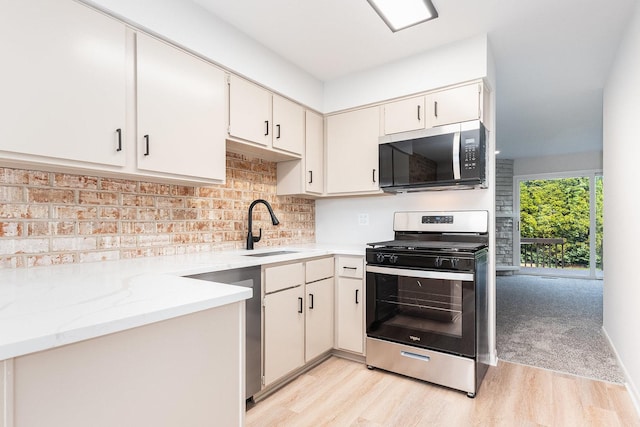 334 Ashland Ave, Highwood, IL 60040 - kitchen with stainless steel appliances, light wood-type flooring, a sink, decorative backsplash, and light stone counters