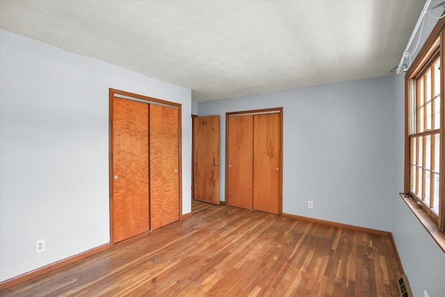 2107 Barberry Dr, Champaign, IL 61821 - unfurnished bedroom with wood-type flooring, baseboards, and multiple windows