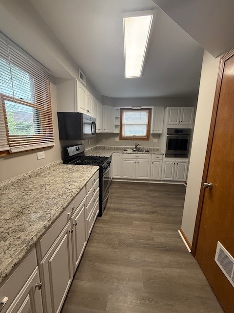 674 E Algonquin Rd, Des Plaines, IL 60016 - kitchen featuring appliances with stainless steel finishes, a sink, white cabinetry, dark wood-style flooring, and light stone countertops