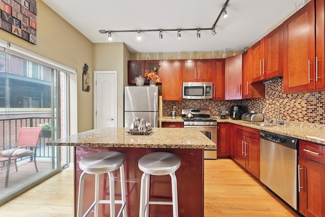 308 E 25th Pl, Chicago, IL 60616 - kitchen featuring stainless steel appliances, light wood-style floors, a kitchen island, a sink, and tasteful backsplash
