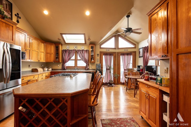 17207 Chase Rd, Dekalb, IL 60115 - kitchen featuring stainless steel appliances, lofted ceiling, a ceiling fan, brown cabinets, and a kitchen bar