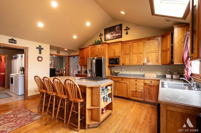 17207 Chase Rd, Dekalb, IL 60115 - kitchen with stainless steel appliances, a kitchen breakfast bar, brown cabinetry, a kitchen island, and a sink