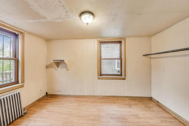 7649 S Dobson Ave, Chicago, IL 60619 - unfurnished room with radiator, light wood finished floors, baseboards, and a textured ceiling