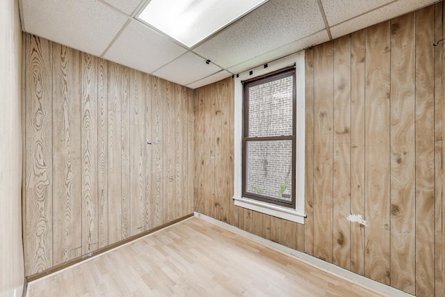 7649 S Dobson Ave, Chicago, IL 60619 - unfurnished room featuring a paneled ceiling, wooden walls, wood finished floors, plenty of natural light, and baseboards