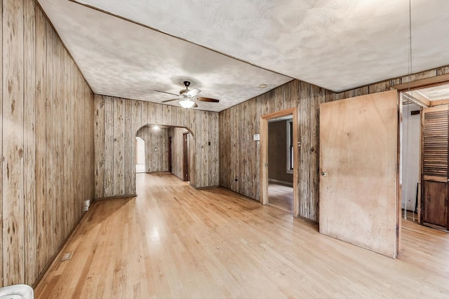 7649 S Dobson Ave, Chicago, IL 60619 - unfurnished room featuring arched walkways, ceiling fan, wood finished floors, and wooden walls
